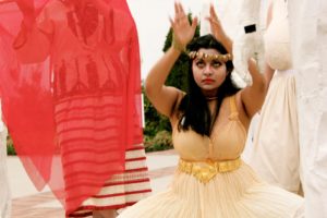 An Indian woman in ceremonial dress with her hands outstretched above her.